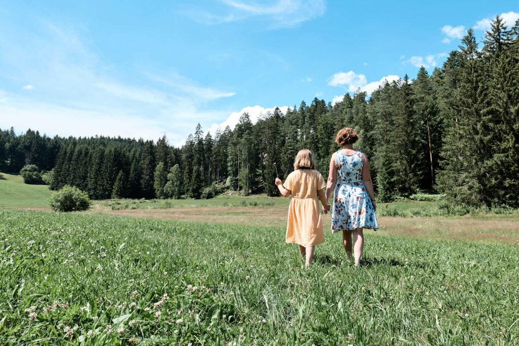 Mutter und Tochter schlendern über die Wiese zum Kamp